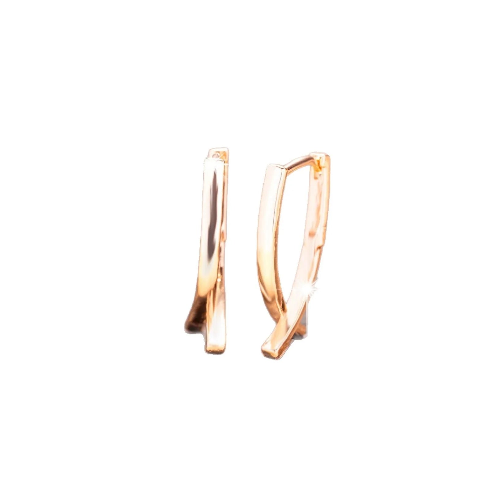 A pair of rose gold coloured cross shaped earrings on a plain background.