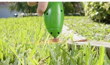 Cordless lawn trimmer with extension pole and protective shield on a garden background