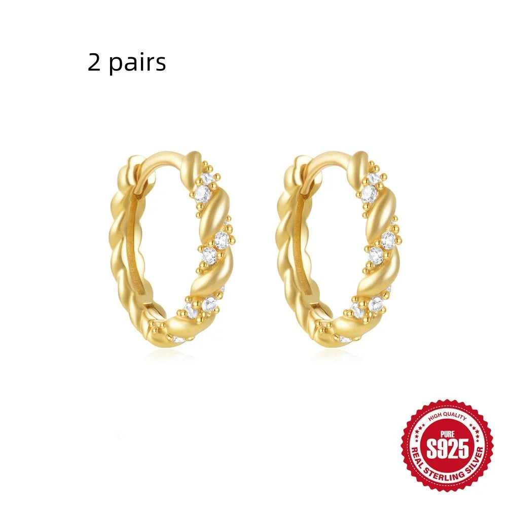 A pair of small, round, geometric stud earrings made of sterling silver with an electroplated finish.