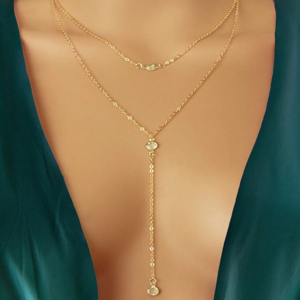 Female gold alloy O-ring chain necklace with geometric pendant on a light background