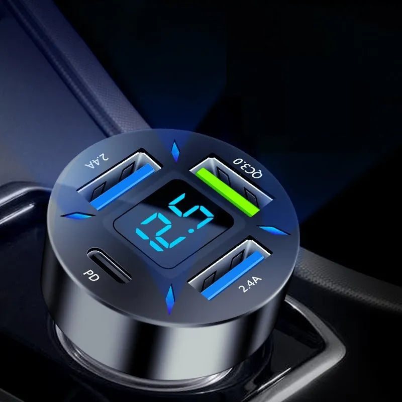 Black four-port USB car charger with digital LED display, shown plugged into a car dashboard.