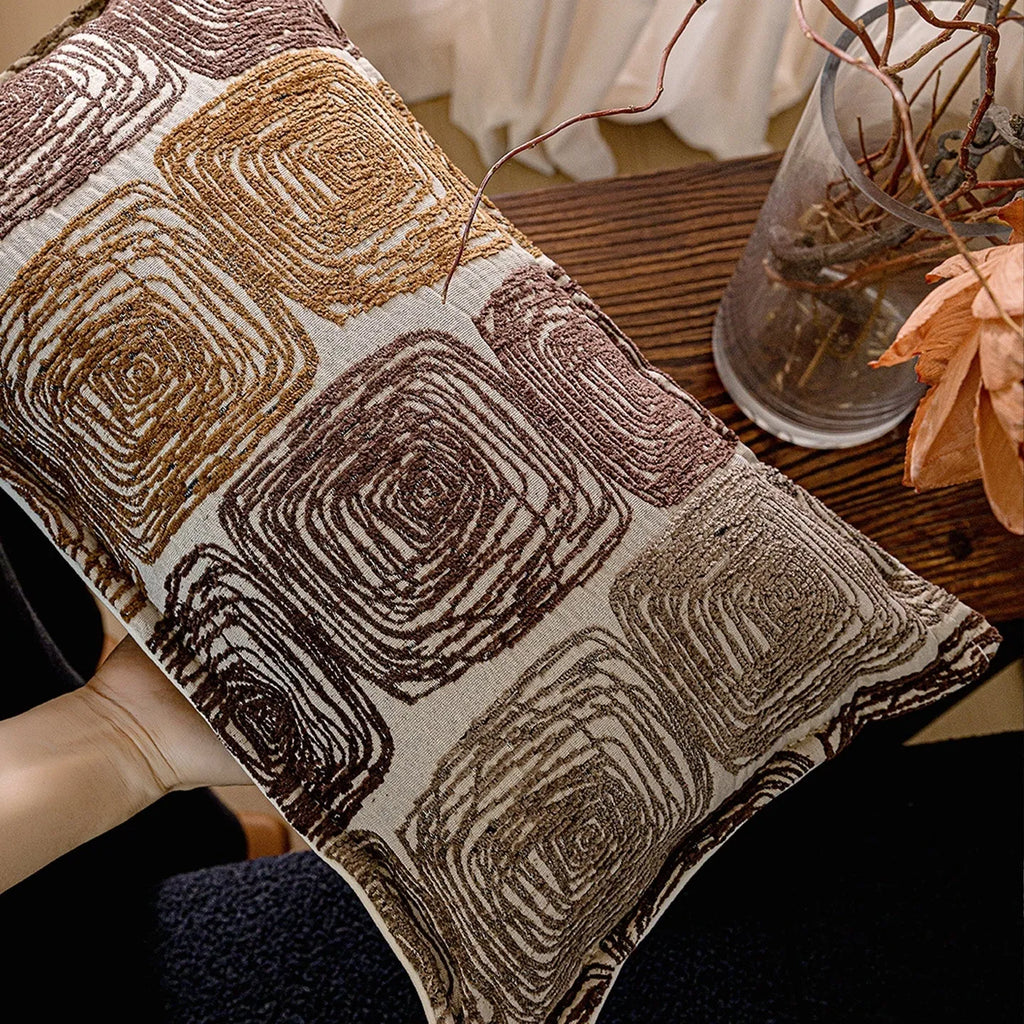 Cream and coffee abstract coil pattern pillow cover on a grey sofa