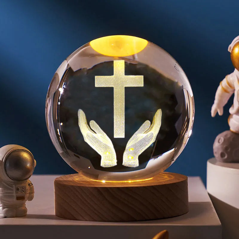White crystal ball ornament on wood base with warm light and religious symbols