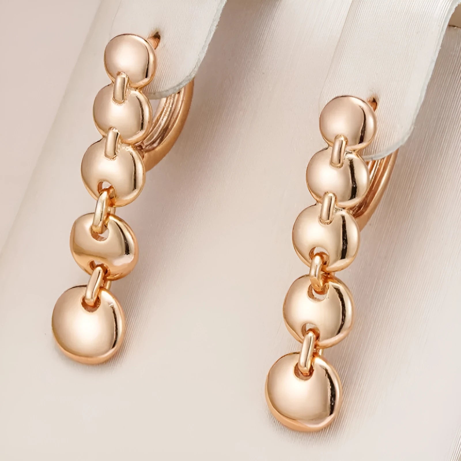 A pair of long, round, gold-toned retro earrings with a woven copper design.