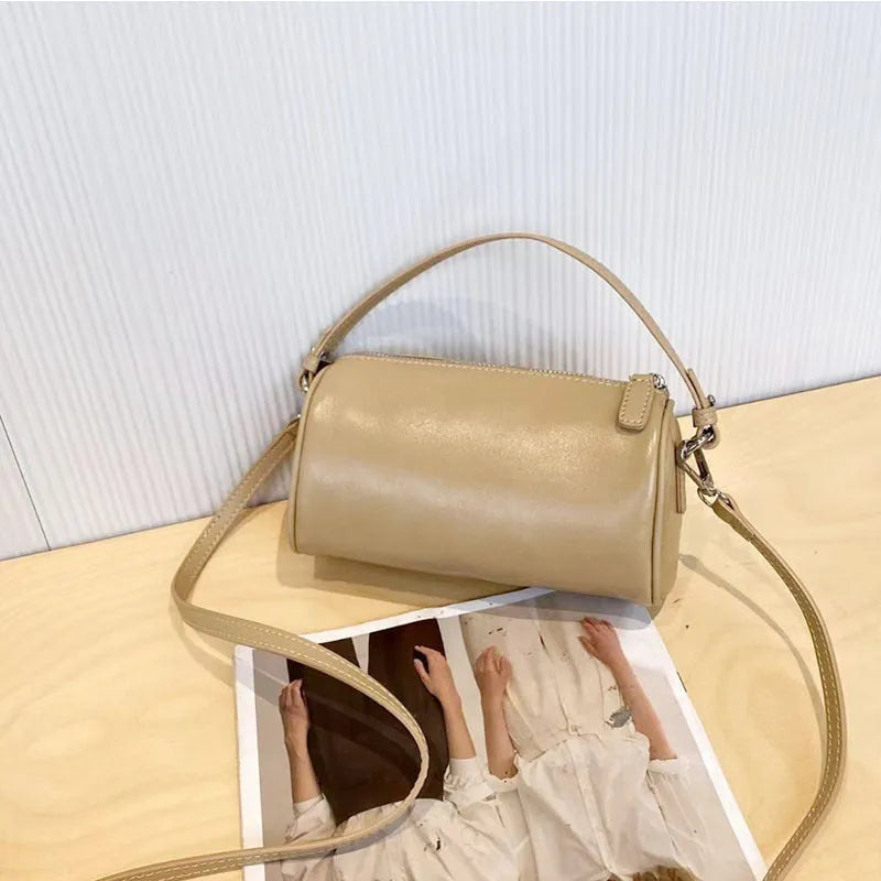Soft genuine leather cylindrical crossbody phone bag in brown with a single shoulder strap.