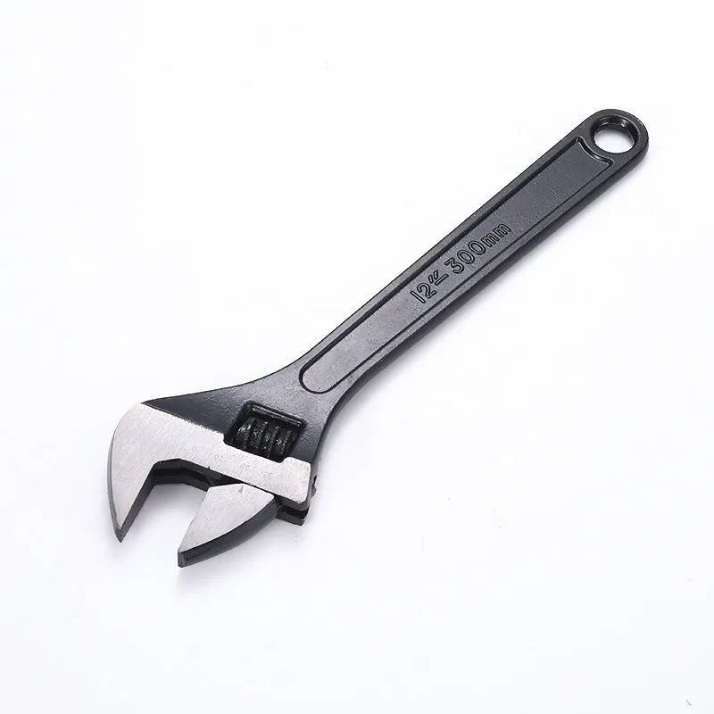Blackened high-carbon steel adjustable open-end wrench with ergonomic handle on a workbench.