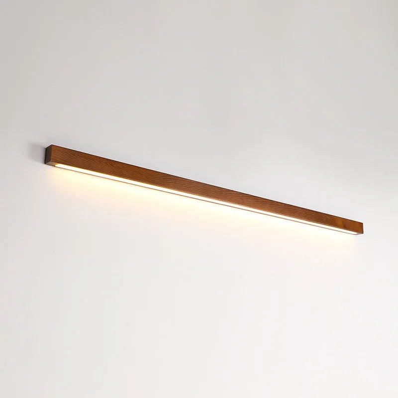Walnut colour wood and acrylic wall lamp strip with LED lighting in a minimalist design on a wall.