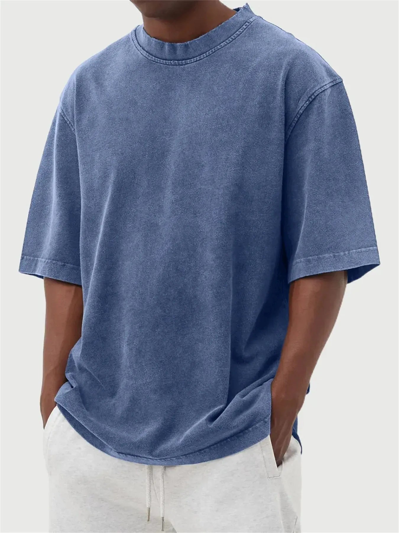 Man wearing a loose-fit, stone-washed grey t-shirt with a distressed solid colour finish and half sleeves.