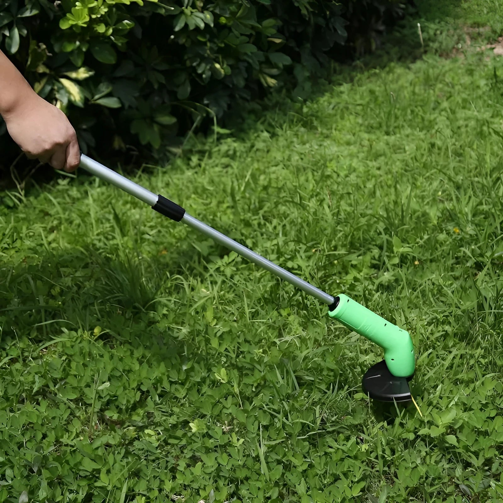 Cordless lawn trimmer with extension pole and protective shield on a garden background