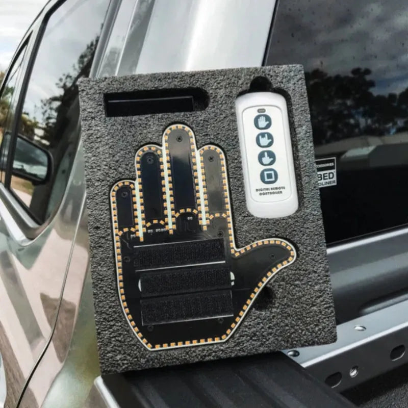 Black plastic LED gesture car light with amber LEDs showing a hand gesture, remote control, and 3M tape for mounting.