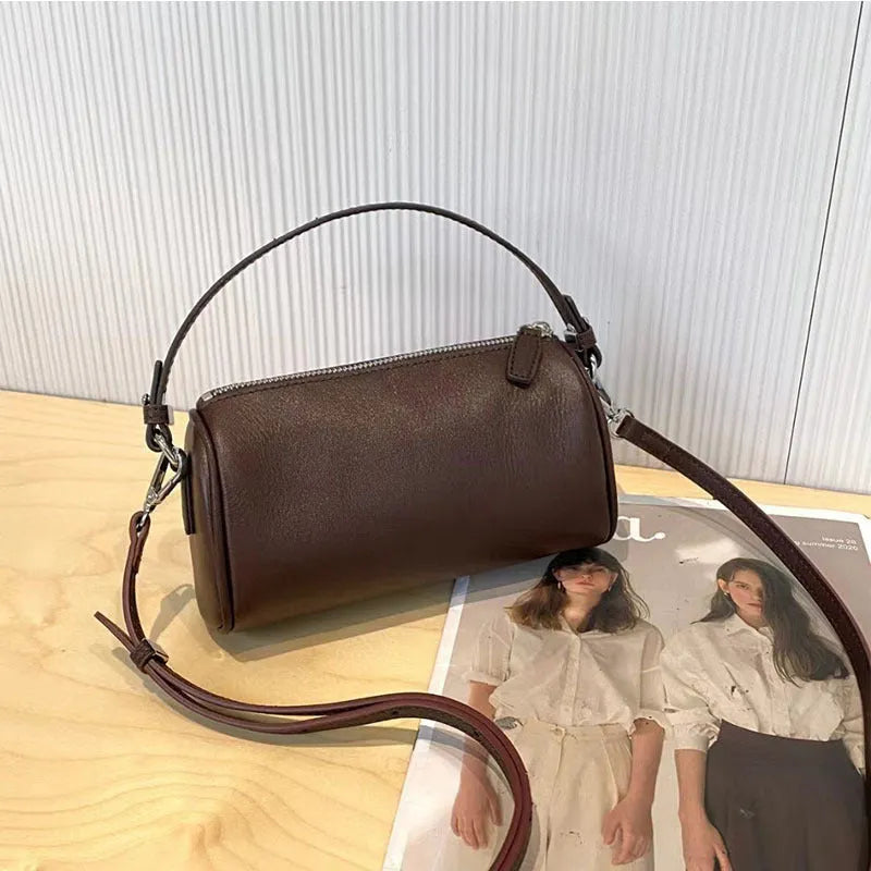 Soft genuine leather cylindrical crossbody phone bag in brown with a single shoulder strap.