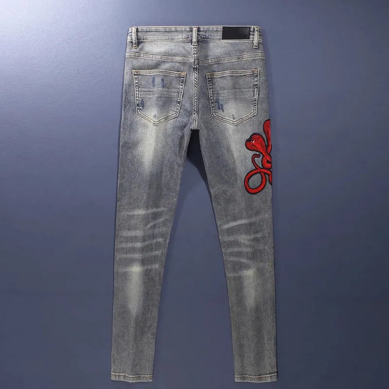 Worn looking washed-out slim fit jeans with hole patches and embroidered brand detail in old colour