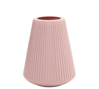 Simple plastic decorative flower vase in blue, green, pink, or white on a desktop.