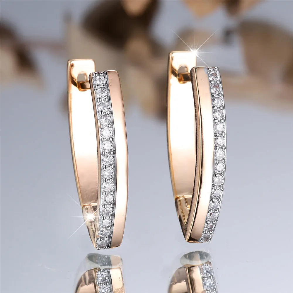Close-up of women's geometric V-shaped clip-on earrings in champagne gold with white diamond details on a copper base.
