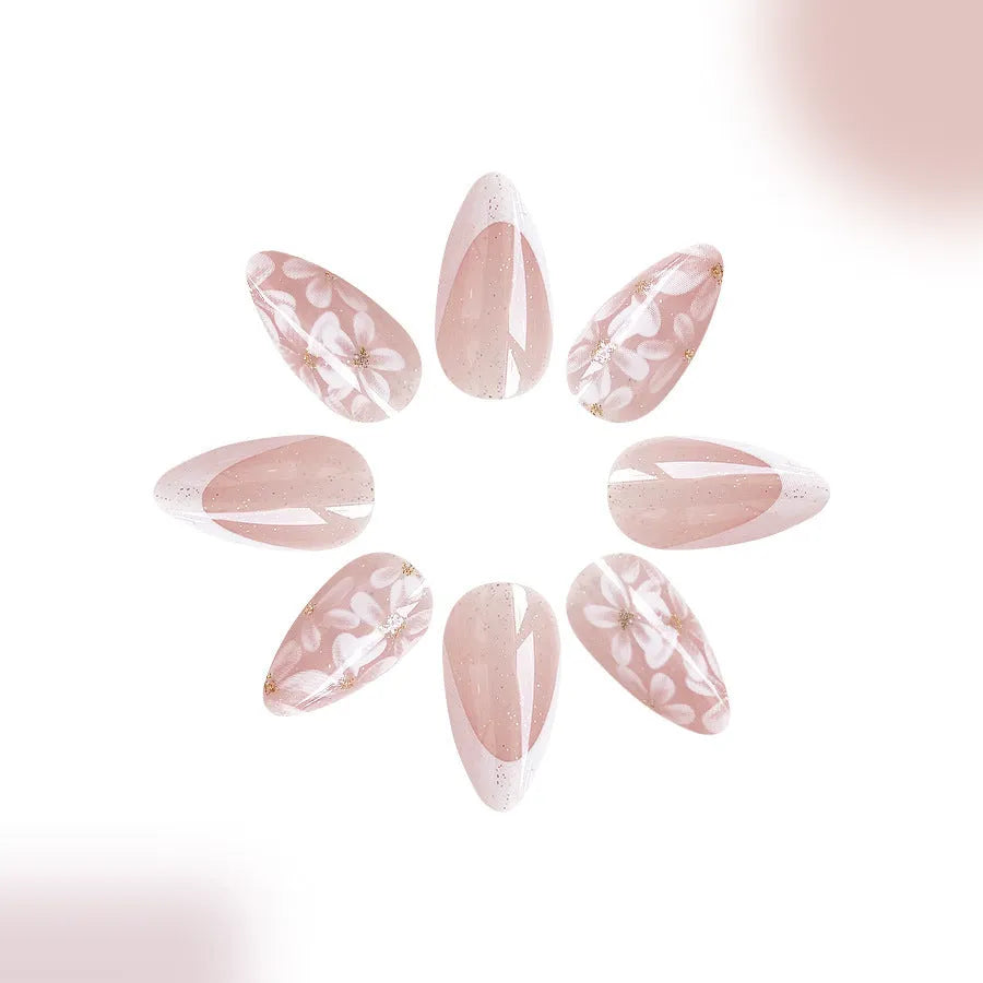 Short almond-shaped press-on nails with French manicure, flower patterns, and glitter accents in colour C625