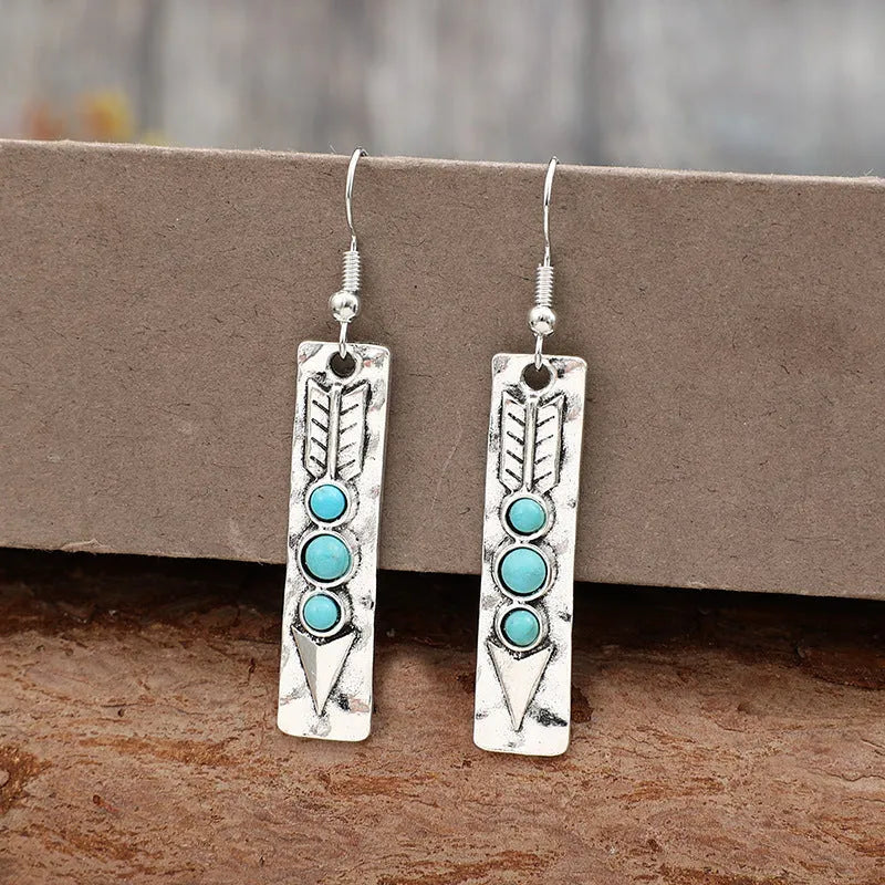 Geometric long silver earrings with blue turquoise inlay detail on a white background.