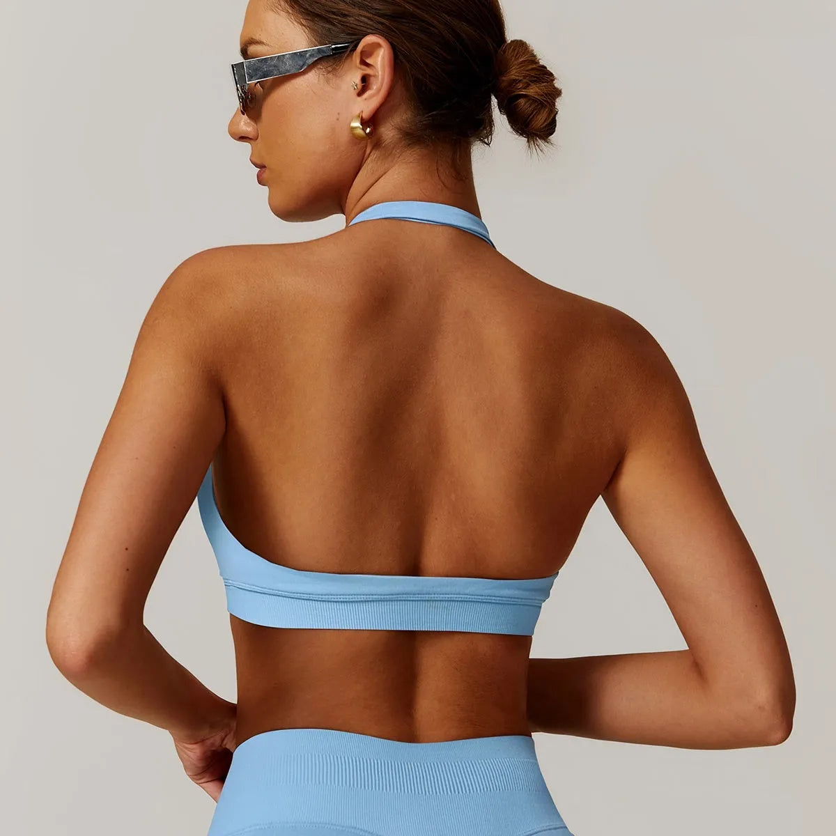 Women's black halter neck sports bra with medium support and hollow back.