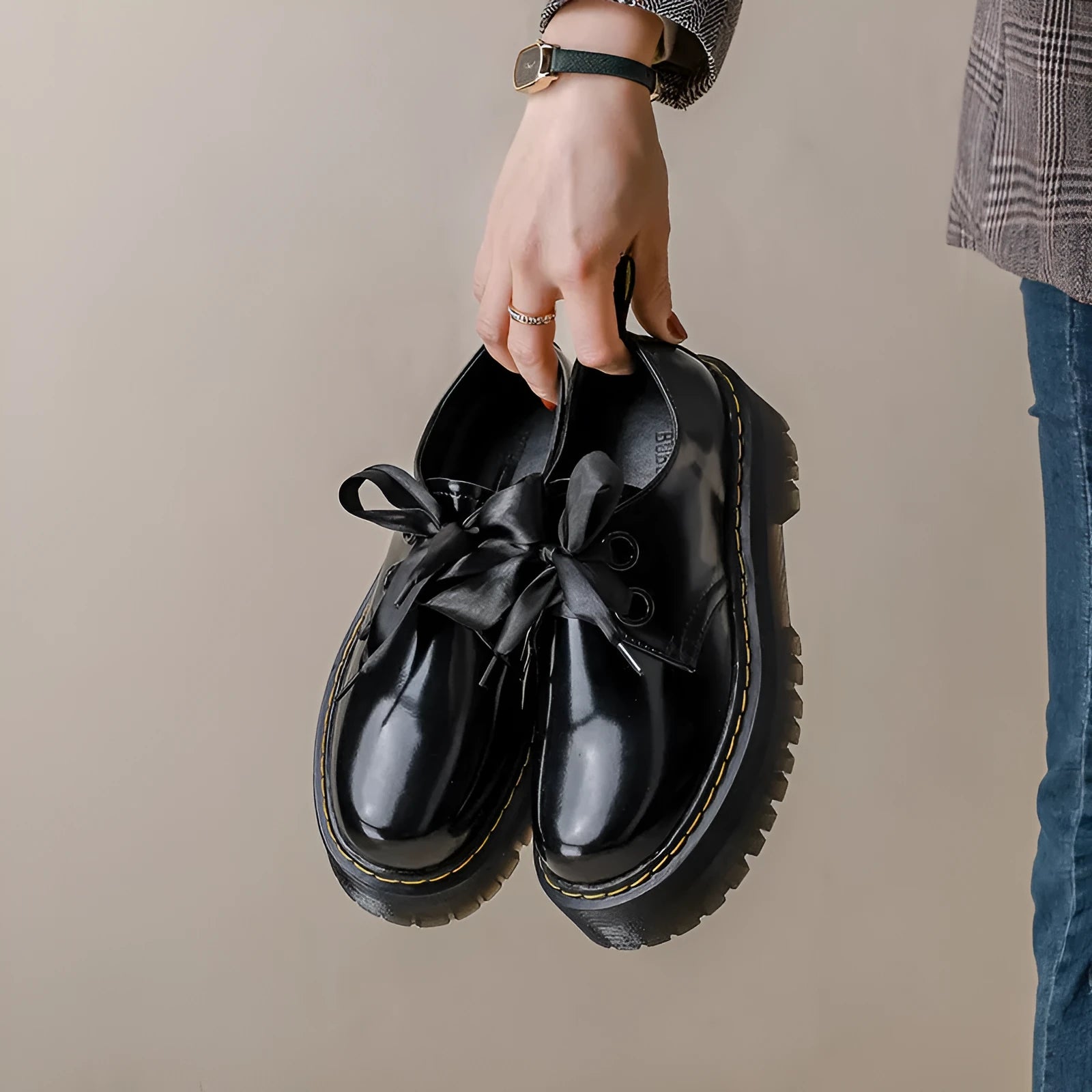 Women's black thick-soled lace-up shoes with ribbon and cross-strap design on a white background.