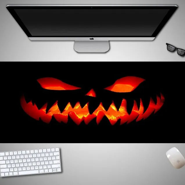 Oversized black Halloween-themed mouse pad with spooky artwork on a desk next to a gaming mouse.