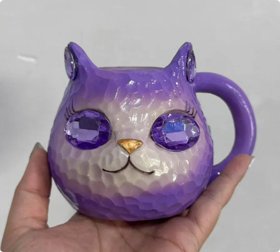 Colourful cat-shaped resin craft ornament in purple, green, blue, or pink on a desk.