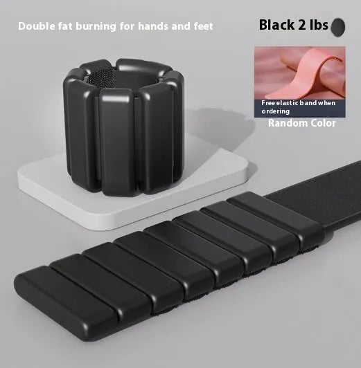 Adjustable black silicone wrist weight bracelet with a detached 2lb metallic weight on a grey background.