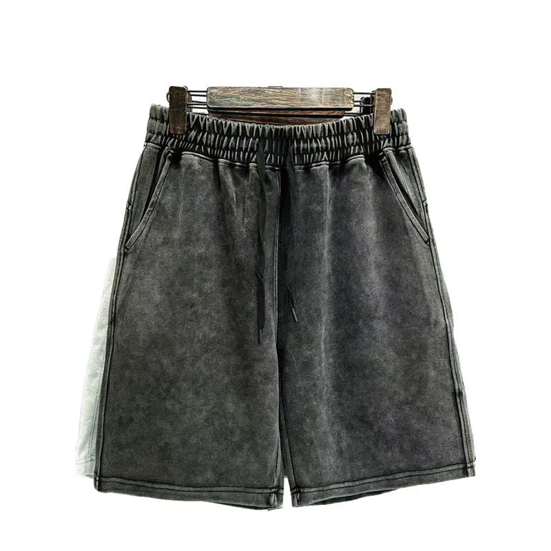 Man wearing charcoal black distressed cotton casual shorts with a loose straight fit.