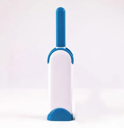 Blue reusable pet hair removal brush with a self-cleaning base, placed on a grey sofa.