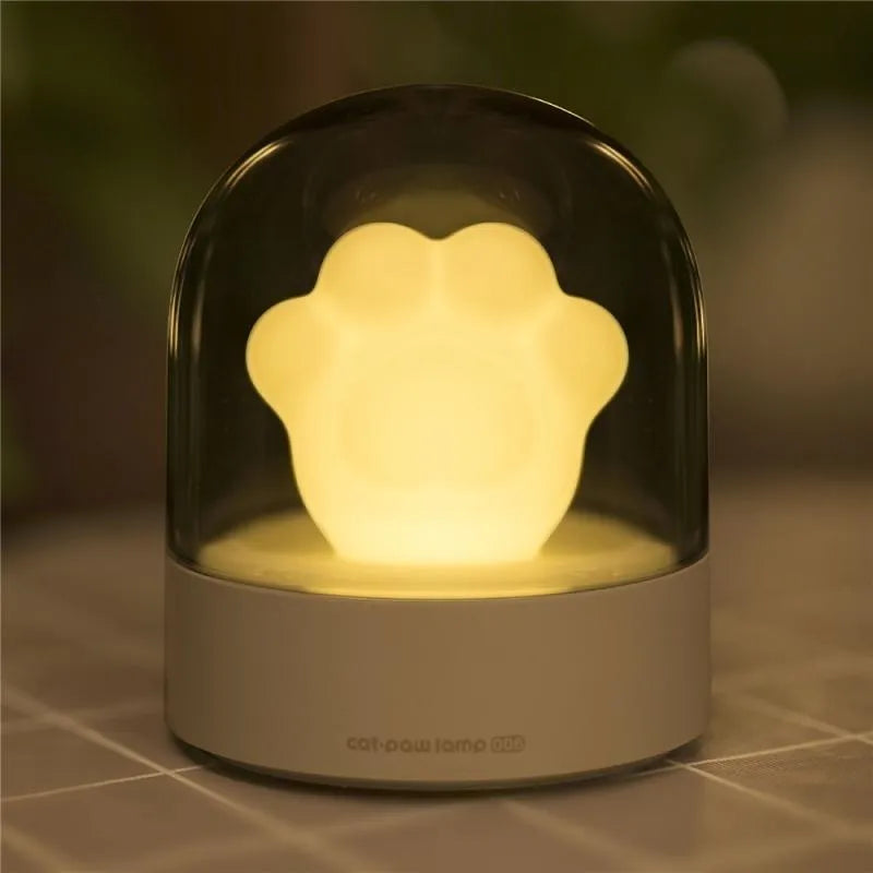 Grey cat paw USB night light with rotating illumination and music box function on wooden desk