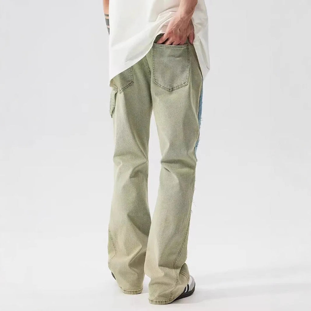 Yellow and blue retro patchwork jeans with splash-ink distressed detailing, showing mid waist and zip fly.