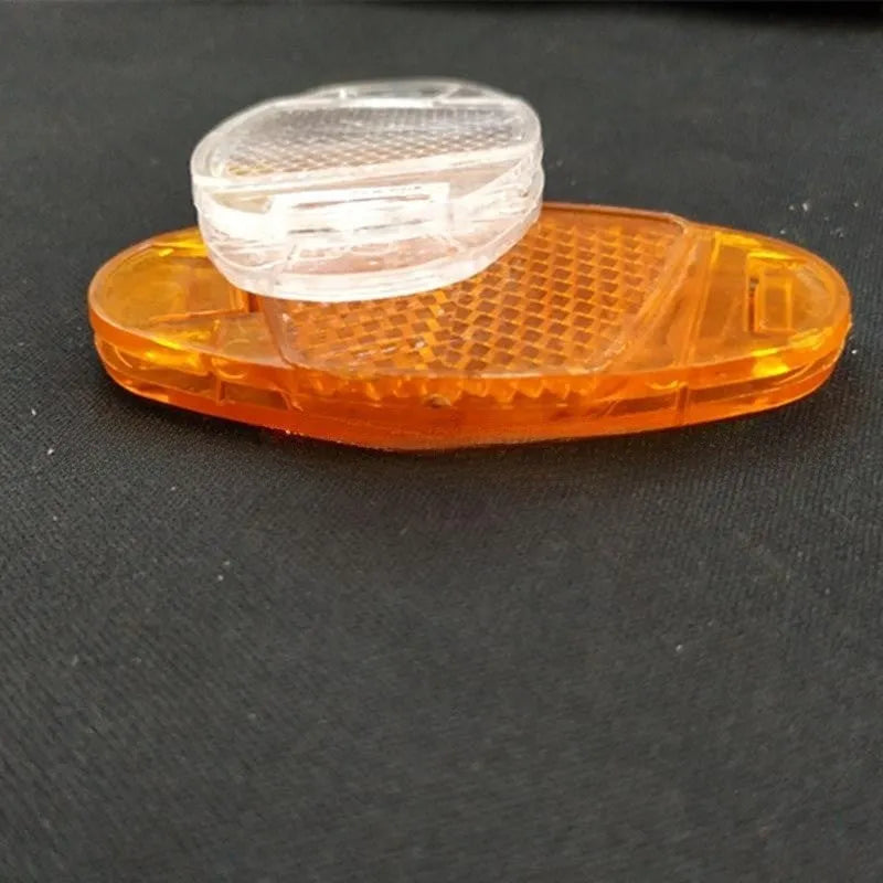 Bicycle spoke reflector showing yellow plastic construction with clip-on attachment for wheel safety