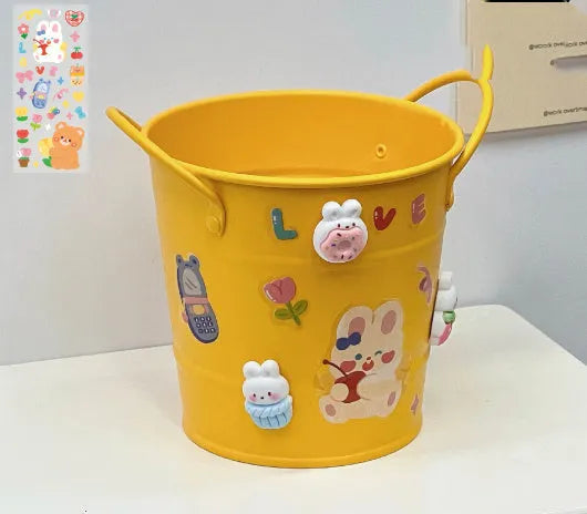 Round metal pen holder in a choice of colours including pink, green, red, white and yellow on a desk.