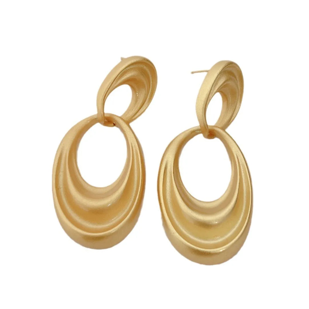 Pair of quicksand gold copper earrings showing a U-shaped design with a double circle detail.