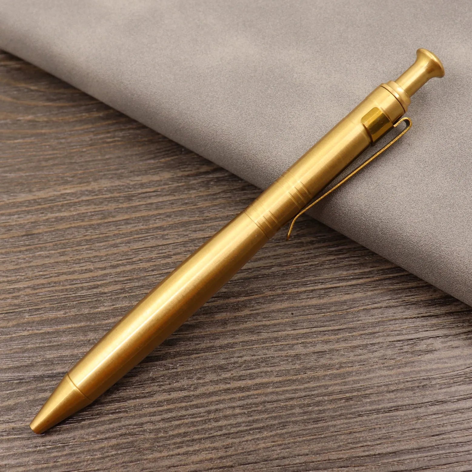 Retro brass tactical pen with cylindrical barrel and six-ring grip, shown with press mechanism extended