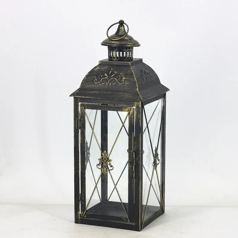 Black wrought iron floor lantern with glass panels on a stone patio.
