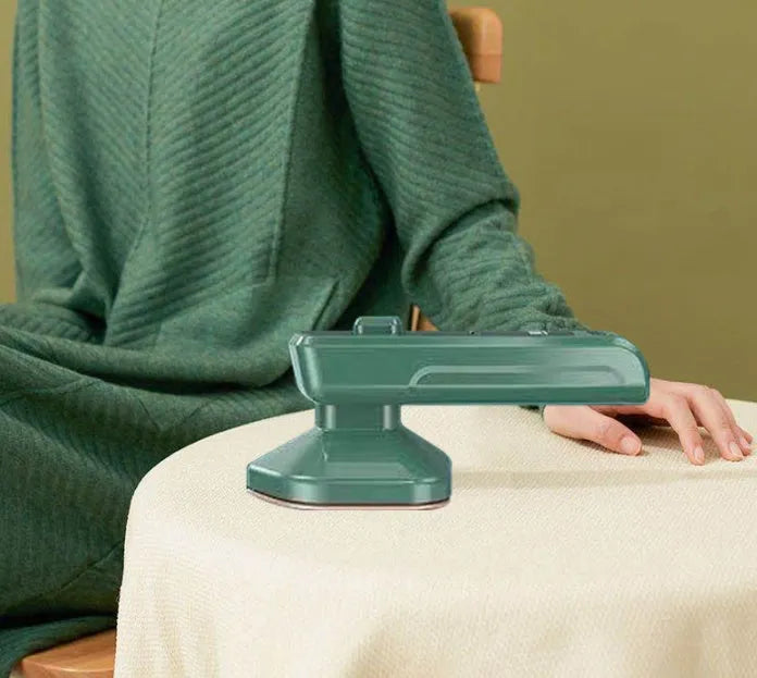 Dark green portable hanging steam iron with ceramic panel and power cord.