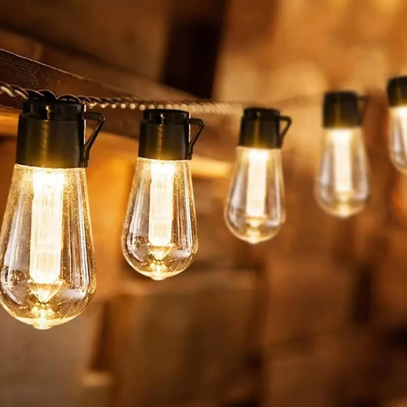 Retro infusion bottle shaped bulb outdoor string lights draped in garden setting