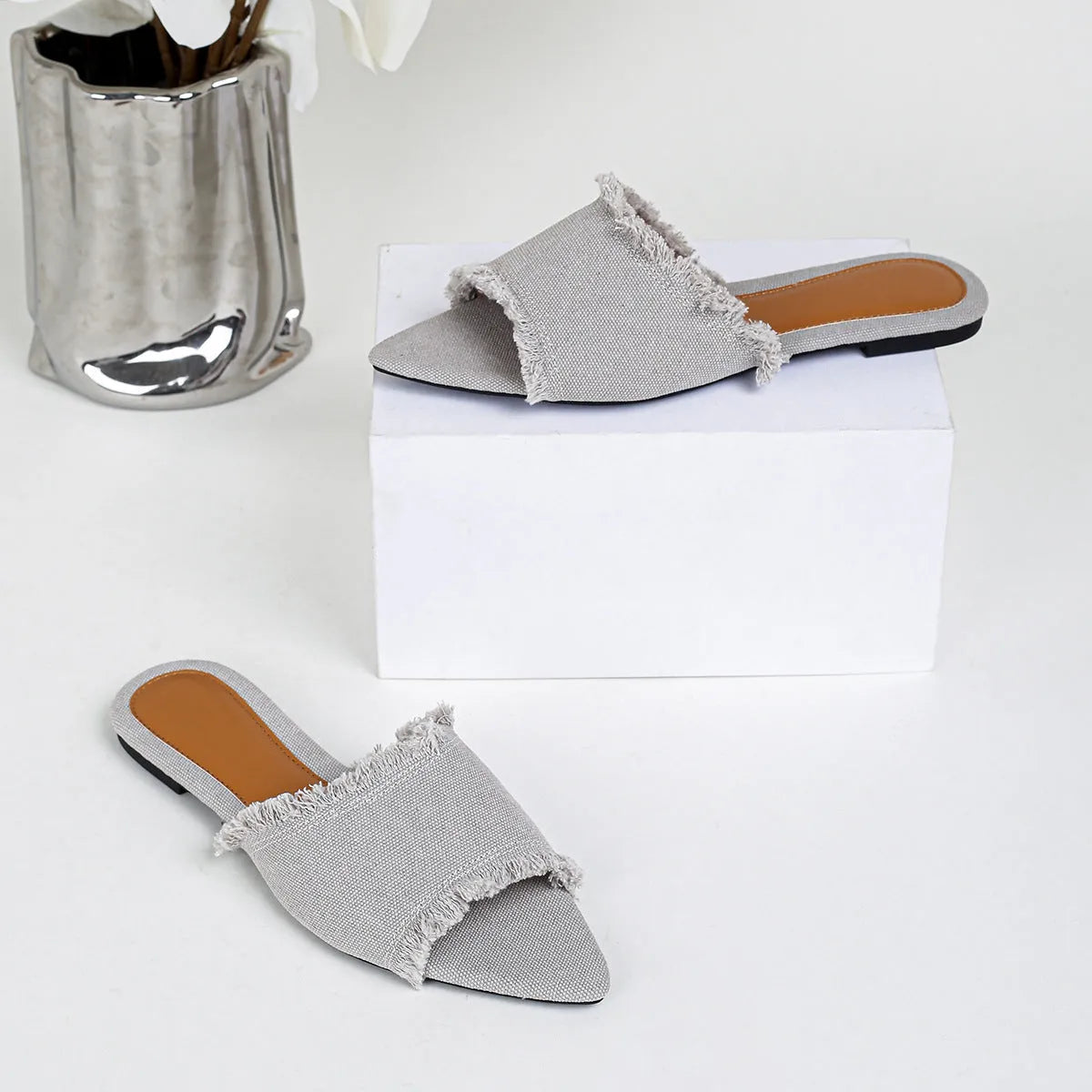 Solid colour denim women's slippers with a tassel detail, showing leather lining and PVC sole.
