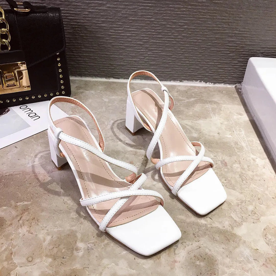 Women's white thick heel roman sandals with overshoot design on a flat background.