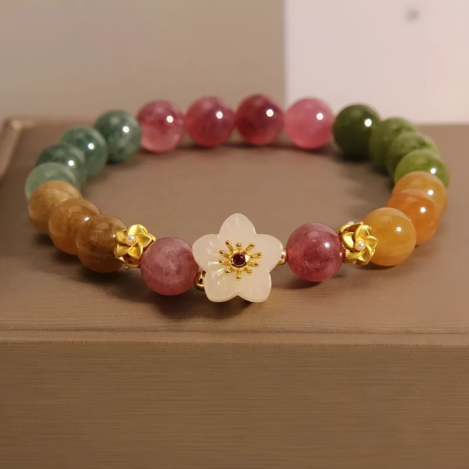 Electroplated tourmaline bracelet with flower and fu character pendant designs in natural colours