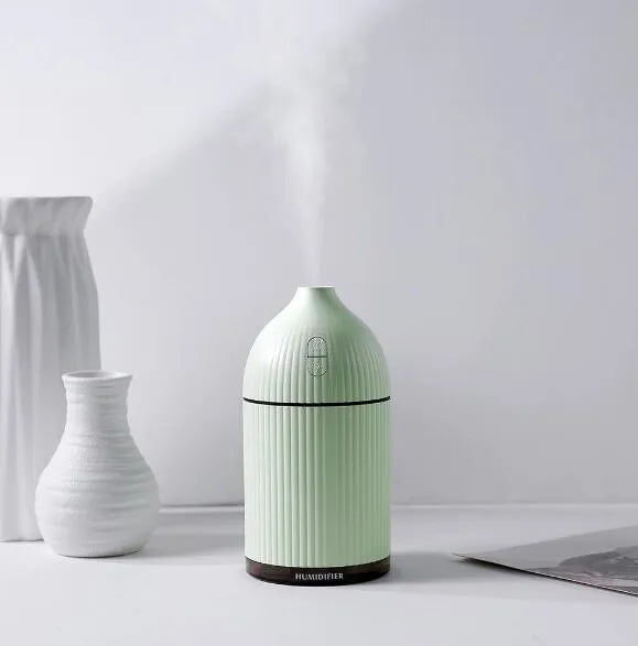 White ultrasonic aromatherapy diffuser with LED light and USB cable on a wooden table