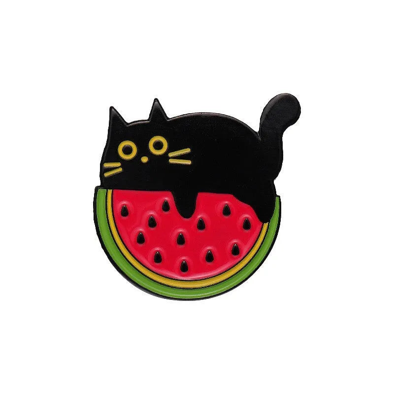 Colourful metal brooch with cartoon fruit and letter design on a blue background.
