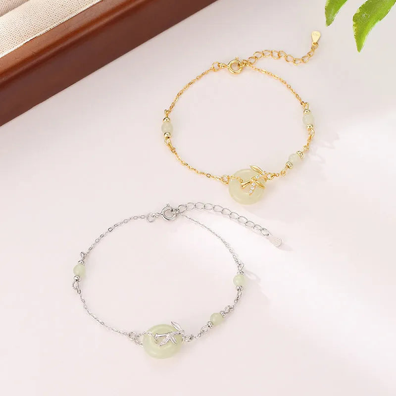 Women's antique style Hetian jade bracelet with a silver peace buckle clasp on a wrist.