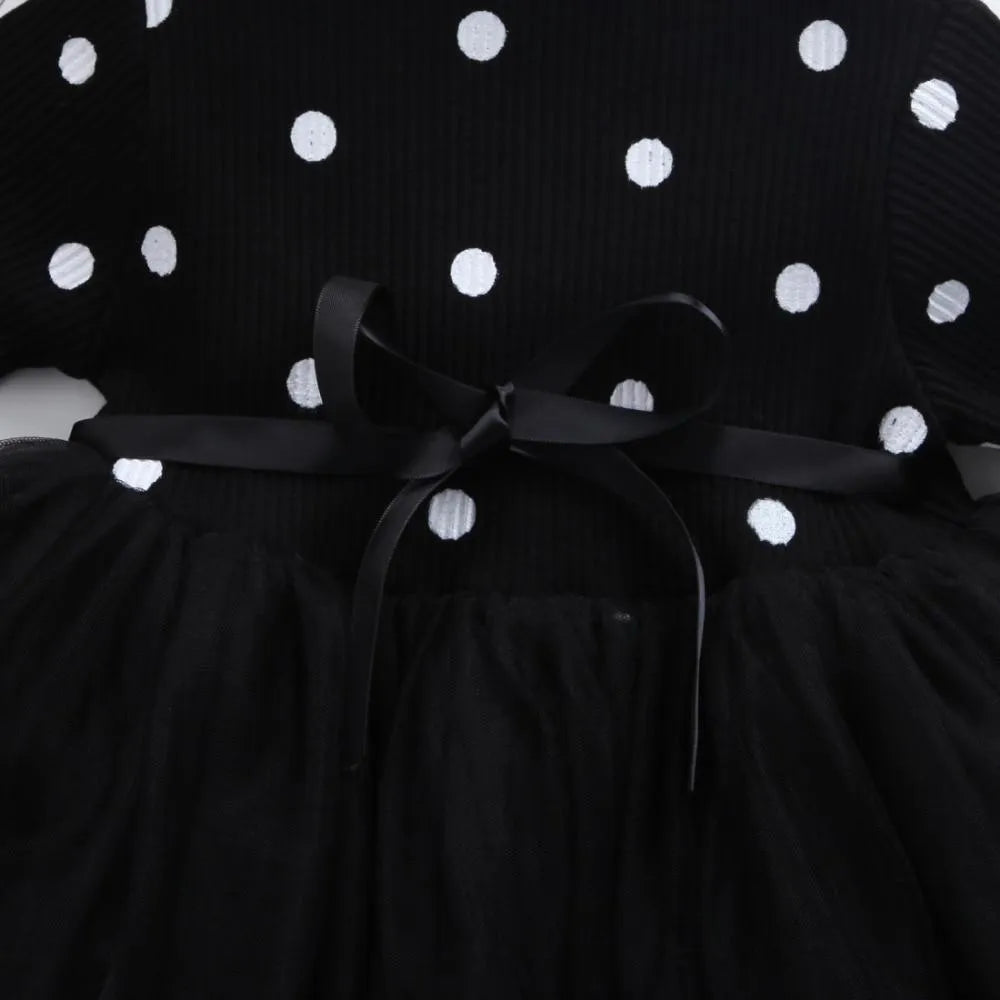 Baby girl in a long sleeve black tutu lace dress for a birthday party or christening