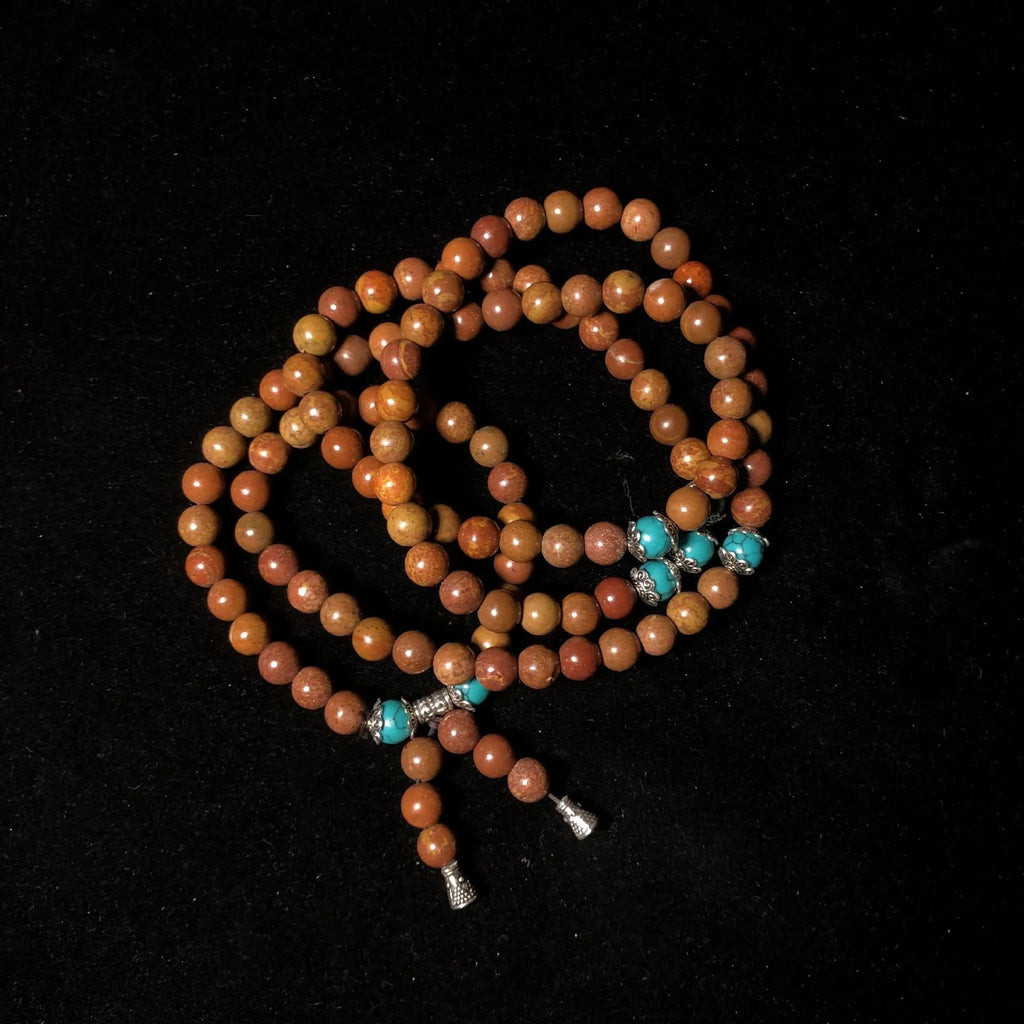 Handmade geometric bracelet with 108 smooth Lvzhu stone beads.