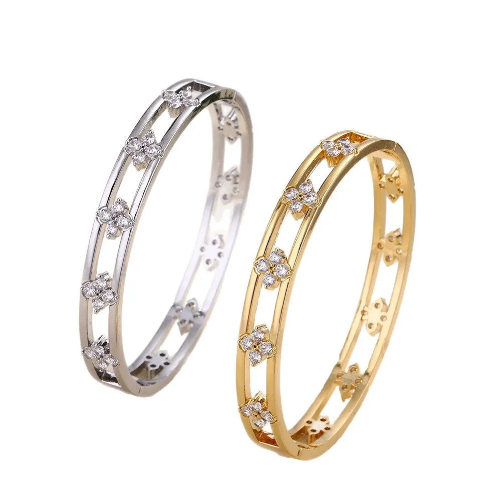 Gold and silver women's hollow bracelets with zircon stones and four-leaf clover charms on a white background.