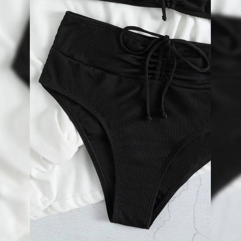 Black women's high-waist bikini with sling split design on shorts and sleeveless top.