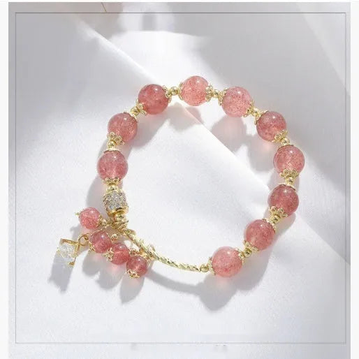Pink women's bracelet with heart-shaped strawberry quartz crystal beads and freshwater pearl accents on a wrist.