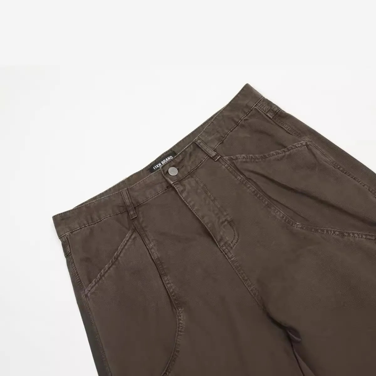Men's brown loose straight leg high waist cotton trousers laid flat.