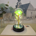Small decorative table lamp with coloured LED lights illuminating plastic flowers under a glass dome.