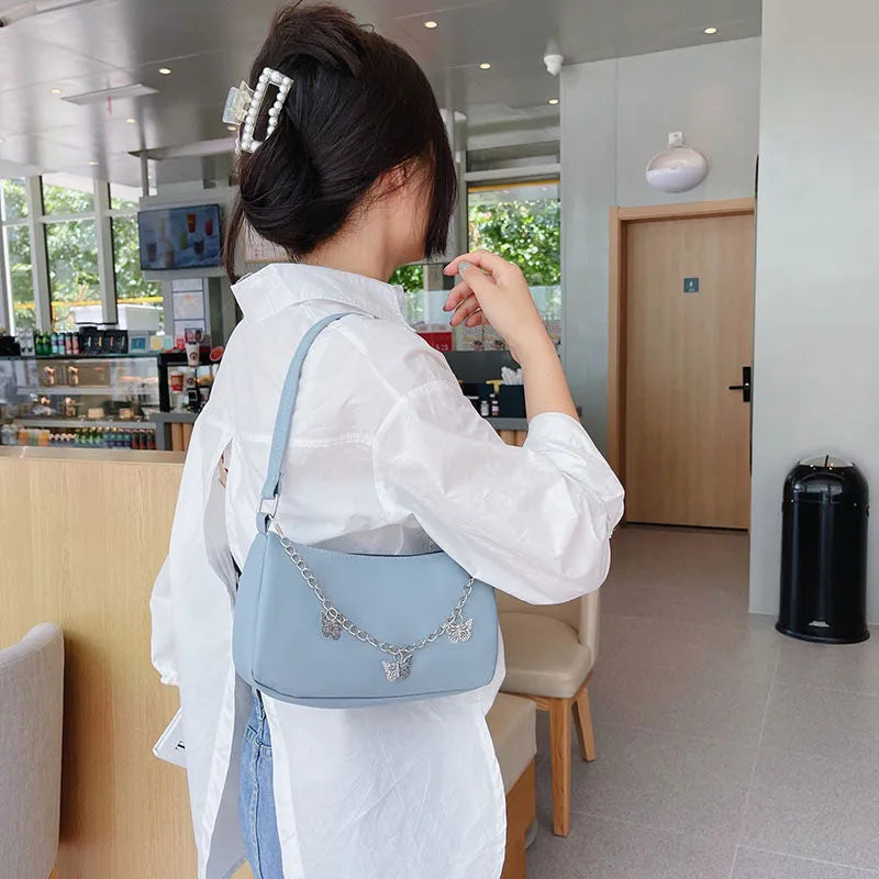 Women's black PU leather crossbody bag with butterfly chain shoulder strap showing internal phone pocket